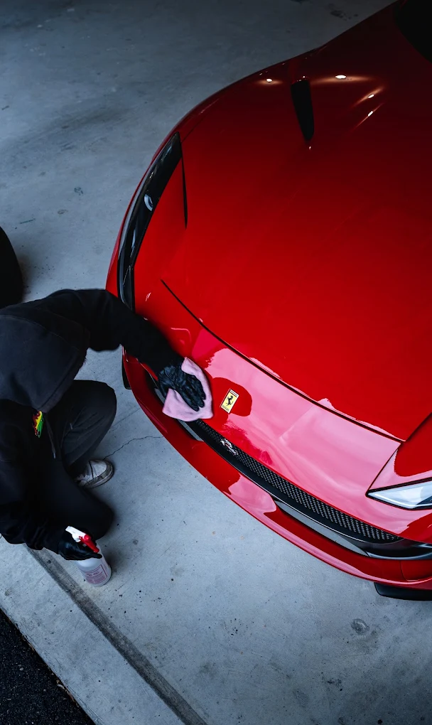 Detailer polishing the hood of a red Ferrari