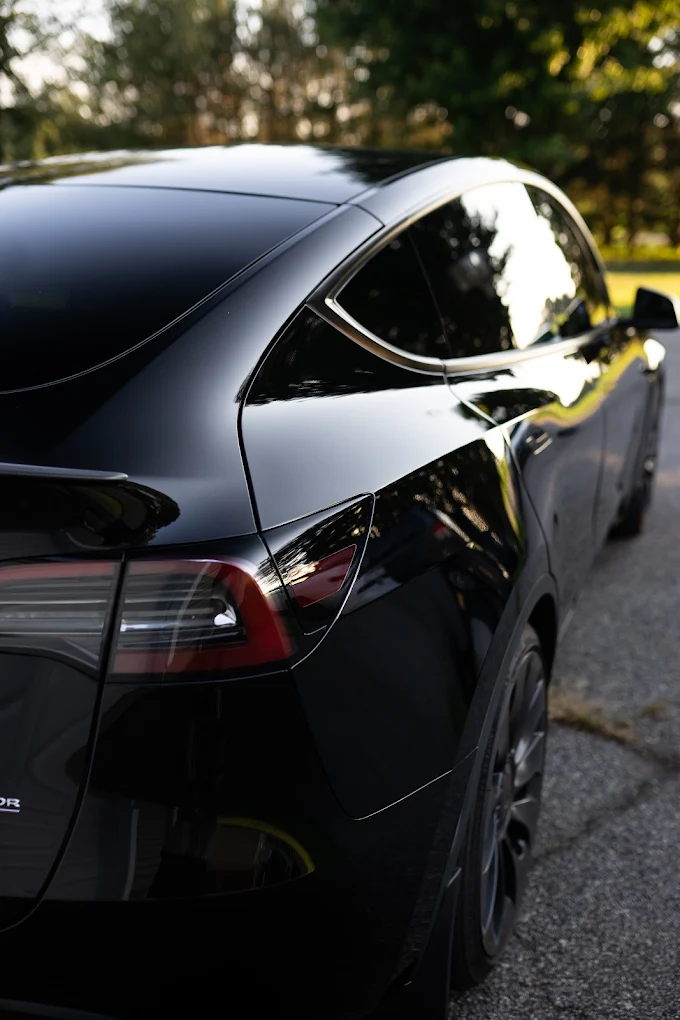 The same Tesla rear quarter panel with deep mirror gloss after paint correction and ceramic coating